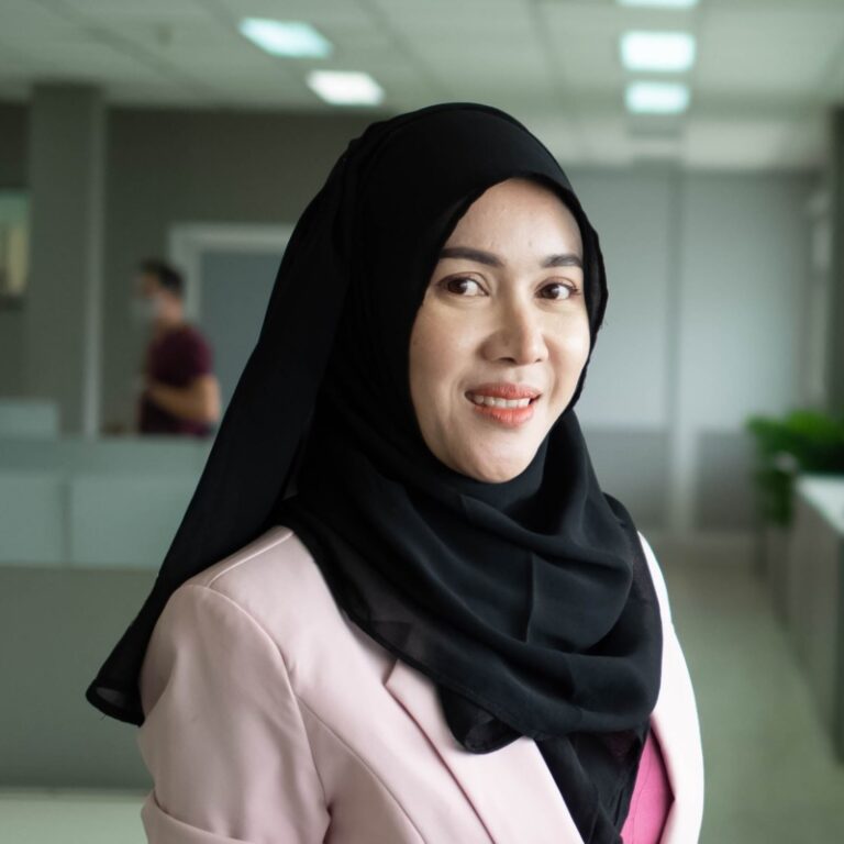 wanita berhijab tersenyum dengan background kantor