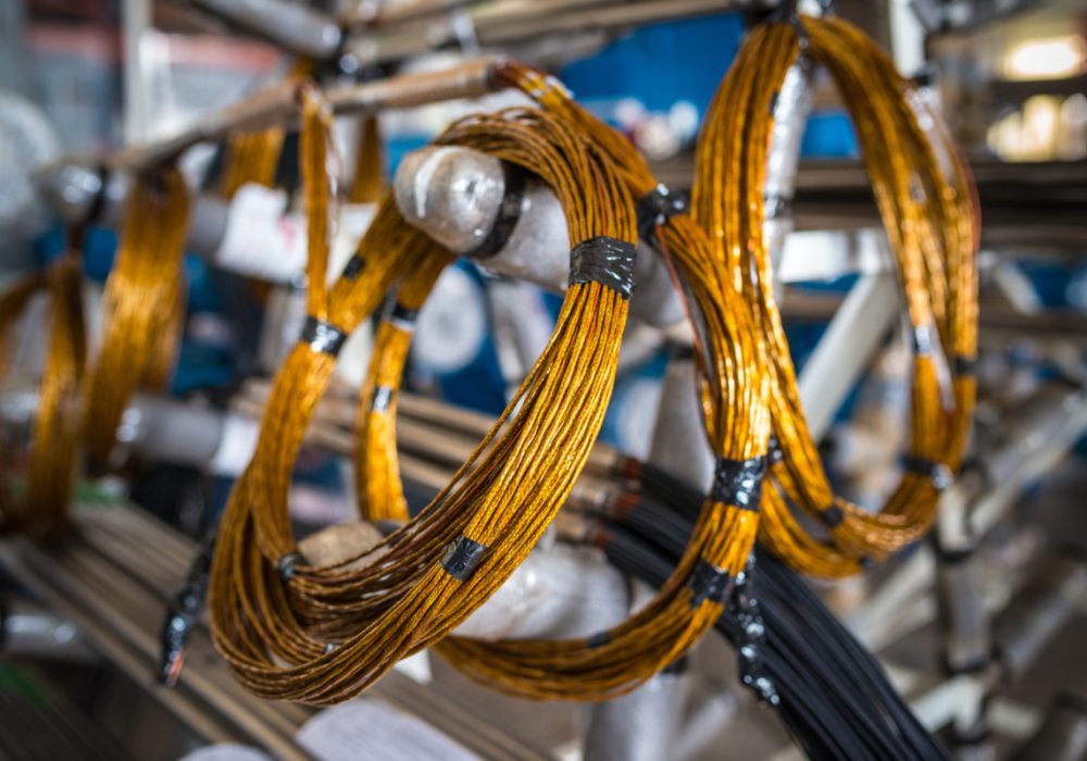 Twisted copper wire hangs on metal racks in the production of large industrial parts and for machine and shipbuilding. Spare parts concept and parts for electronic equipment